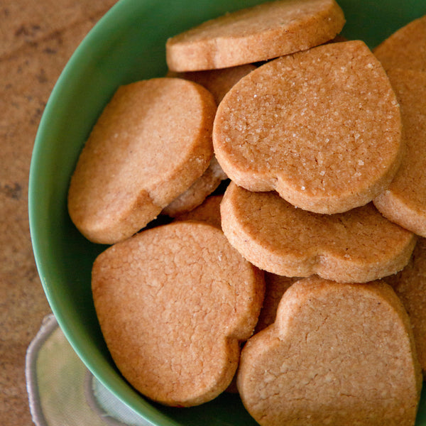 Green bowl filled with heart-shaped cookies on a wooden surface