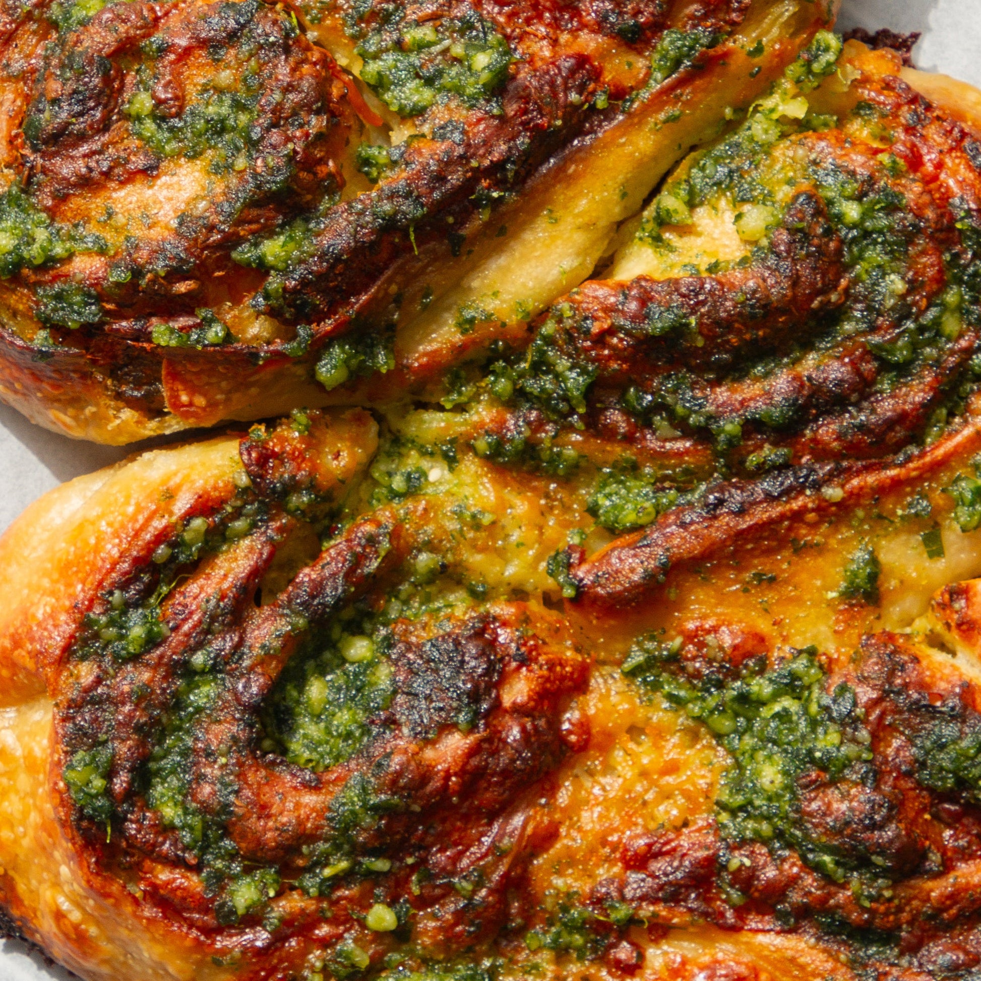 Baked pastry with green herb filling on a white surface